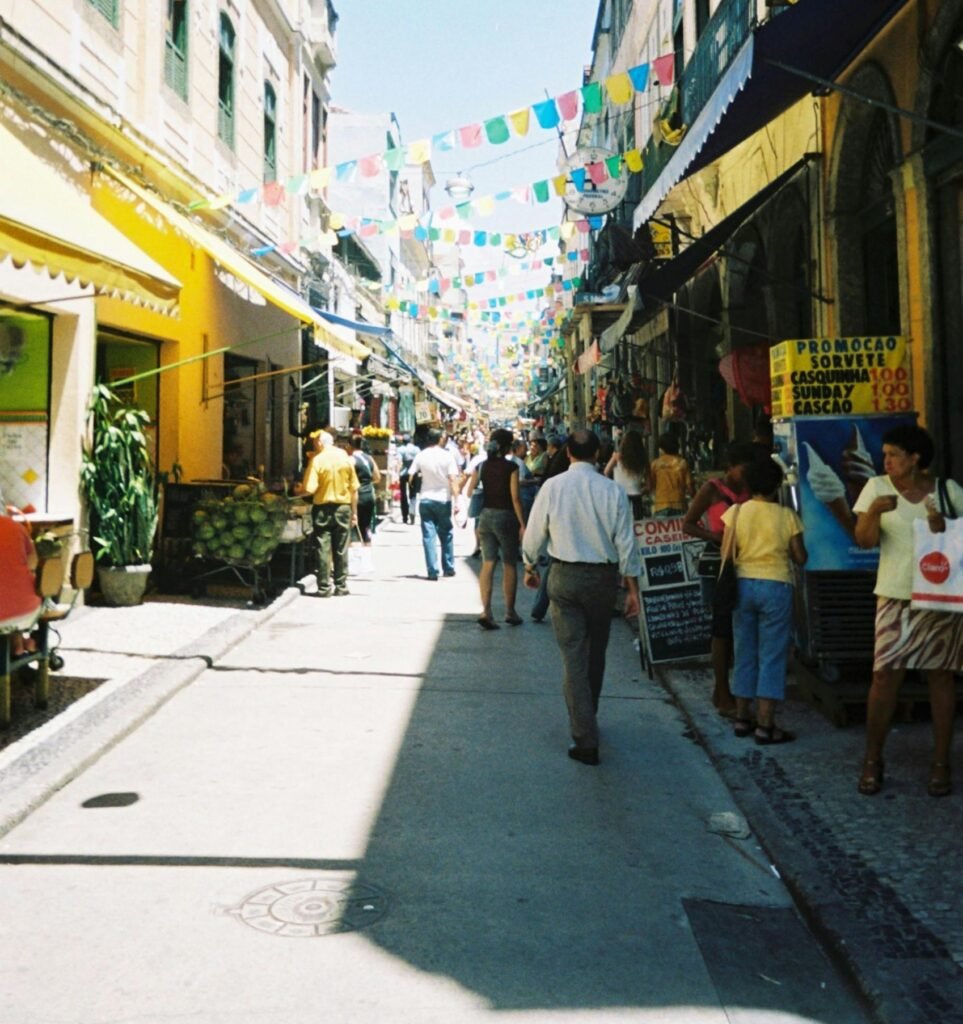 Vibrant street in Rio de Janeiro filled with pedestrians, colorful banners, and bustling shops.