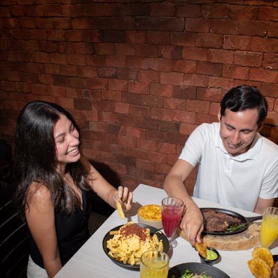 A happy couple enjoys a diverse meal at a cozy indoor restaurant.
