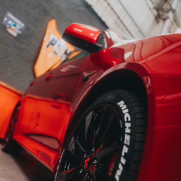 Close-up of a sleek red sports car showcasing a Michelin tire in a garage setting.