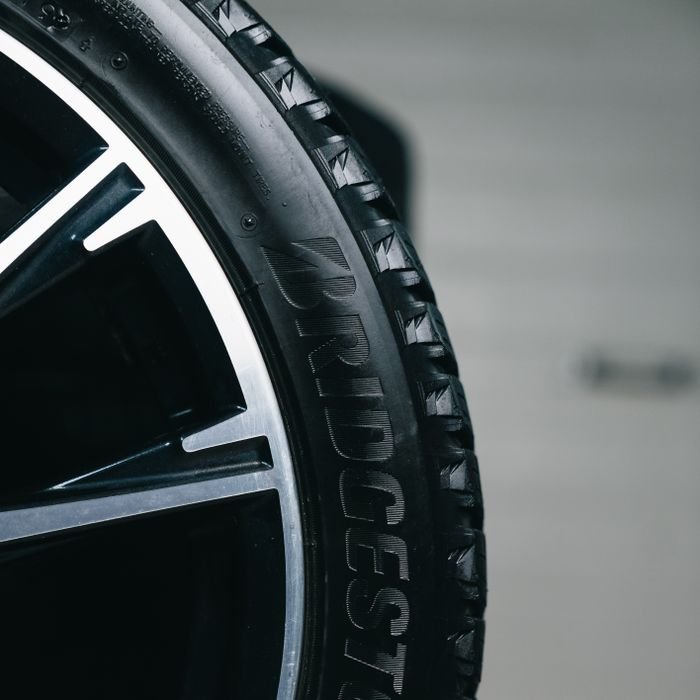 Detailed close-up of a Bridgestone tire mounted on a vehicle, showcasing tread and branding.